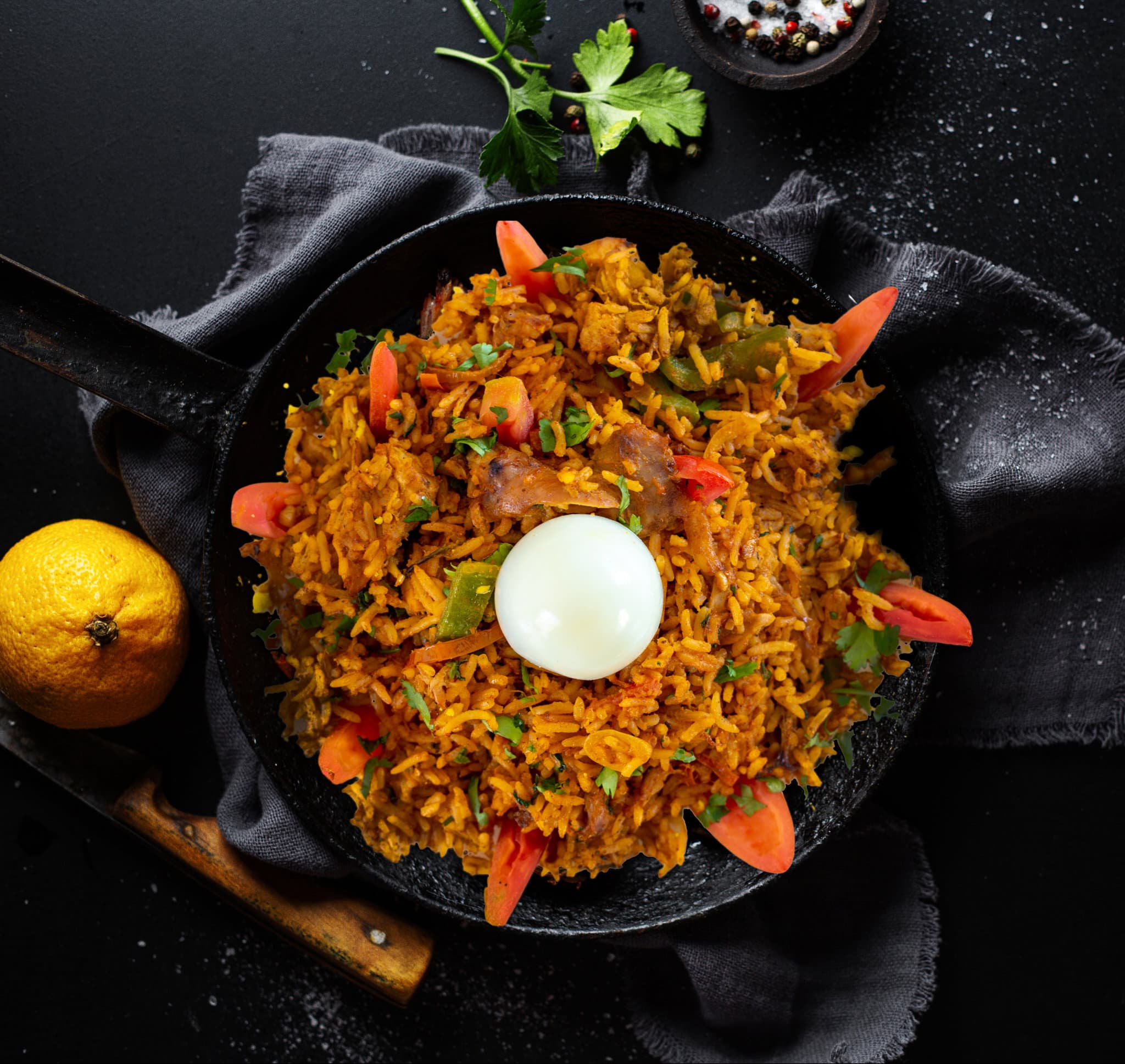 Vegetable biryani garnished with egg and tomato in a pan — food photography Udaipur