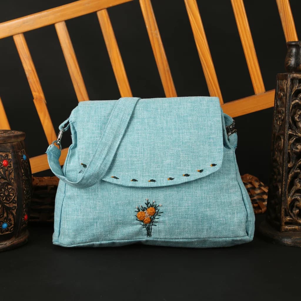Blue embroidered sling bag with floral detail — handbag product photography