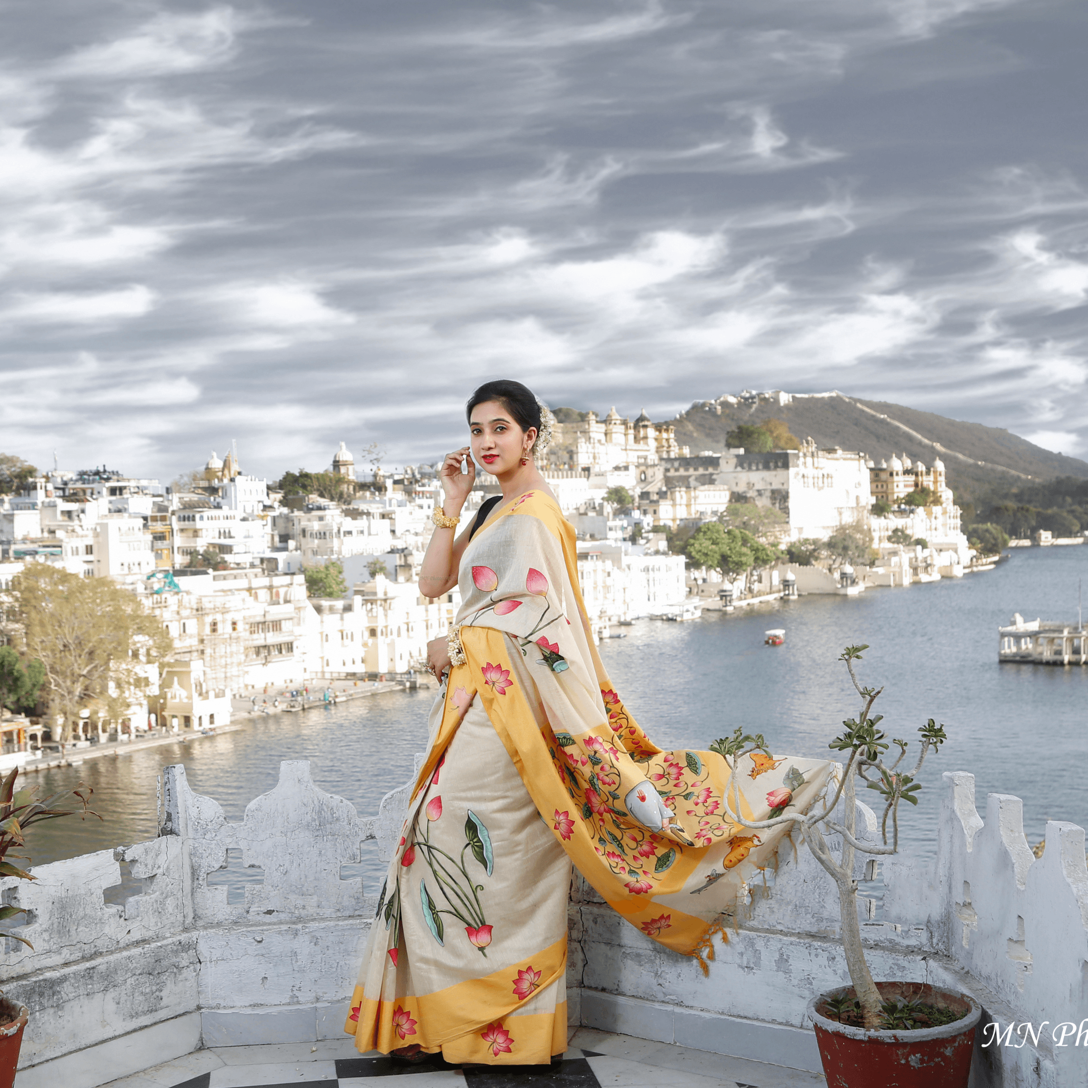 Model in a floral saree on an Udaipur rooftop with city and lake backdrop — fashion photography